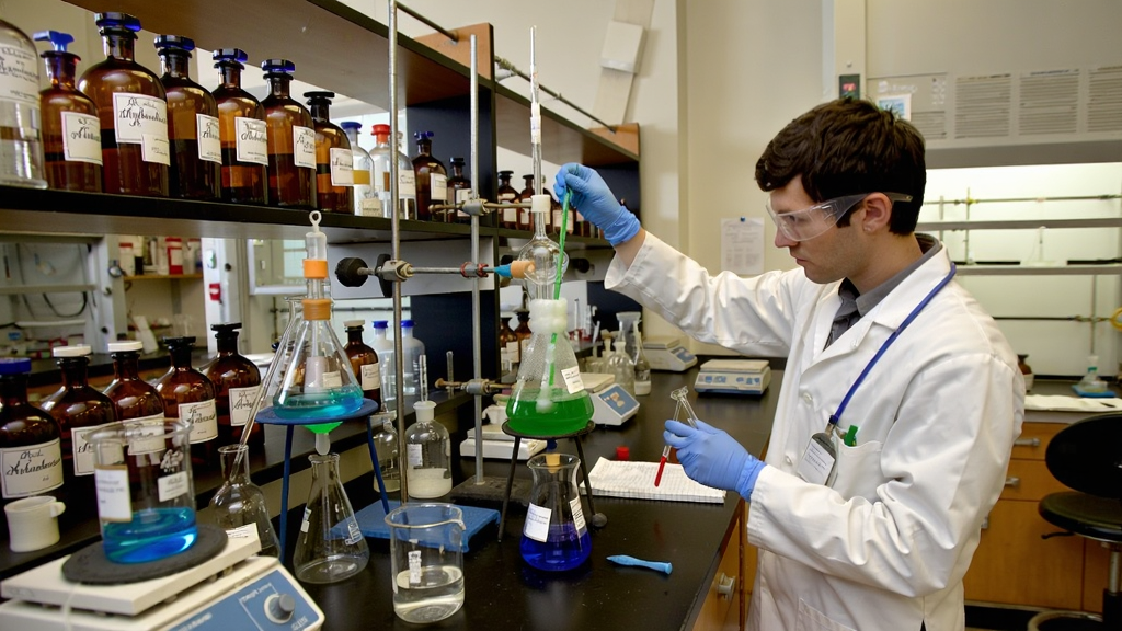化学实验室内的多种试剂瓶和烧杯,一位科学家正在进行反应实验