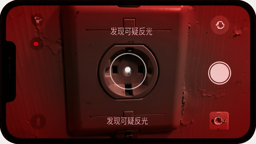 手机屏幕变成红色滤镜取景界面,画面中央对准一个墙壁插座,插座孔内有一个微弱的白色反光点被圆圈标记,布局为取景画面,风格暗色调写实,细节有红色噪点,文字提示“发现可疑反光”,画质干净,无多余元素
