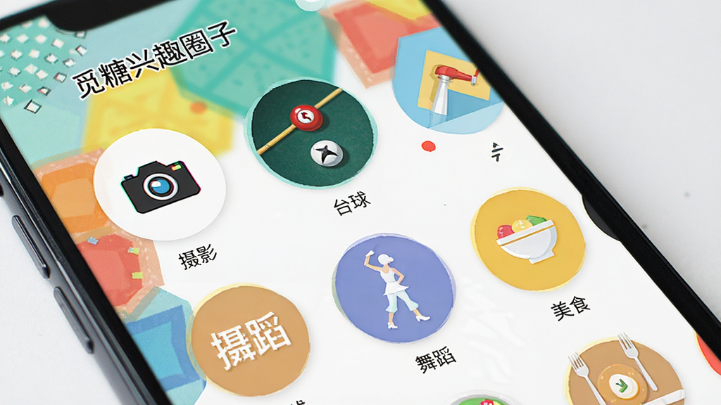 觅糖兴趣圈子页面展示,手机屏幕中显示多个圆形图标,标注“摄影”“台球”“舞蹈”“美食”等字样,背景为多彩几何图形,界面活泼,风格清新,细节丰富,画质干净。