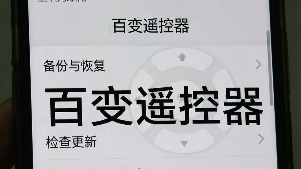一张手机截图风格图片,屏幕显示百变遥控器的设置页面,页面中有“备份与恢复”、“关于我们”、“检查更新”等选项,背景为浅灰色,突出“百变遥控器”名称,画质干净,无多余元素。