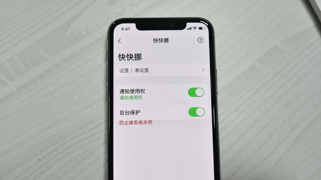 主体:一个智能手机屏幕展示“快快挪”应用的设置页面,高亮显示“通知使用权”和“后台保护”两个选项。布局:手机竖屏居中,背景为浅灰色桌面。排版:设置项清晰,开关按钮为绿色。风格:截屏风格,真实感。细节:在“后台保护”下方有红色文字提示“防止被系统杀死”,画质清晰。